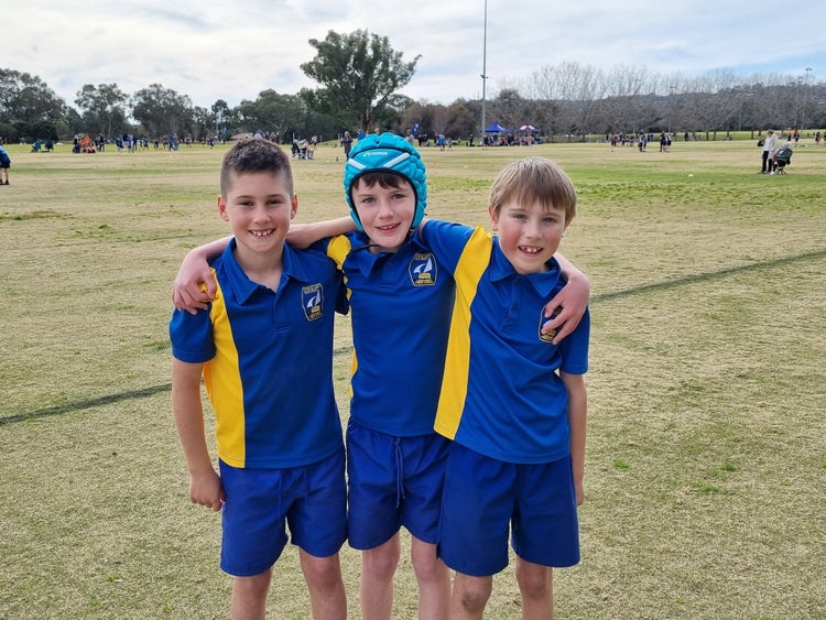 Three students huddled together wearing the LAPS sports. uniform