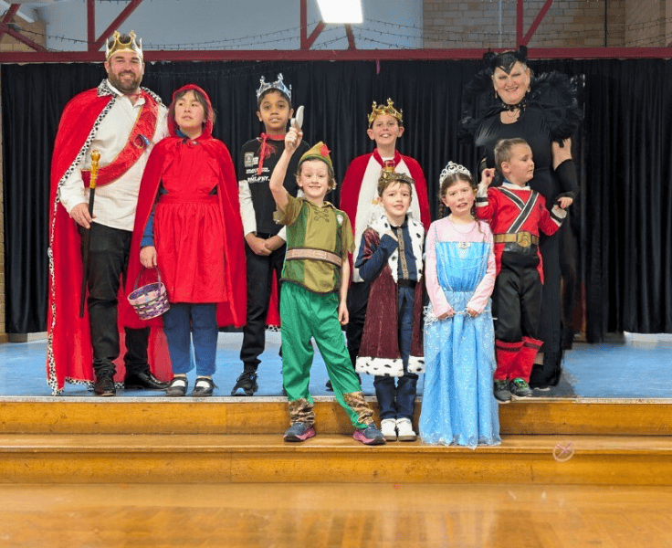 Students and teachers dressed up as characters for Book Week and standing together on a stage.