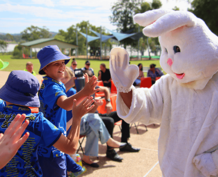 Students hgh fiving a teacher dressed as the Easter Bunny.