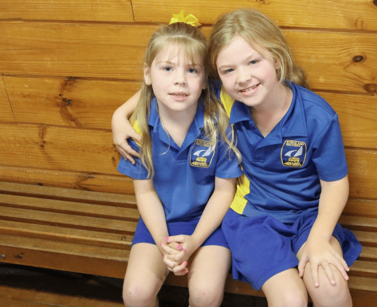 Two students sitting down wearing the LAPS sports uniform.
